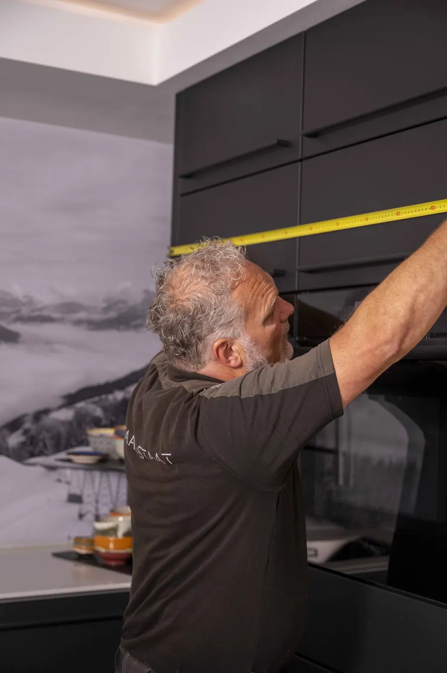 Henk van Veen meet met een meetlint een zwarte keuken van Staal Staat op
