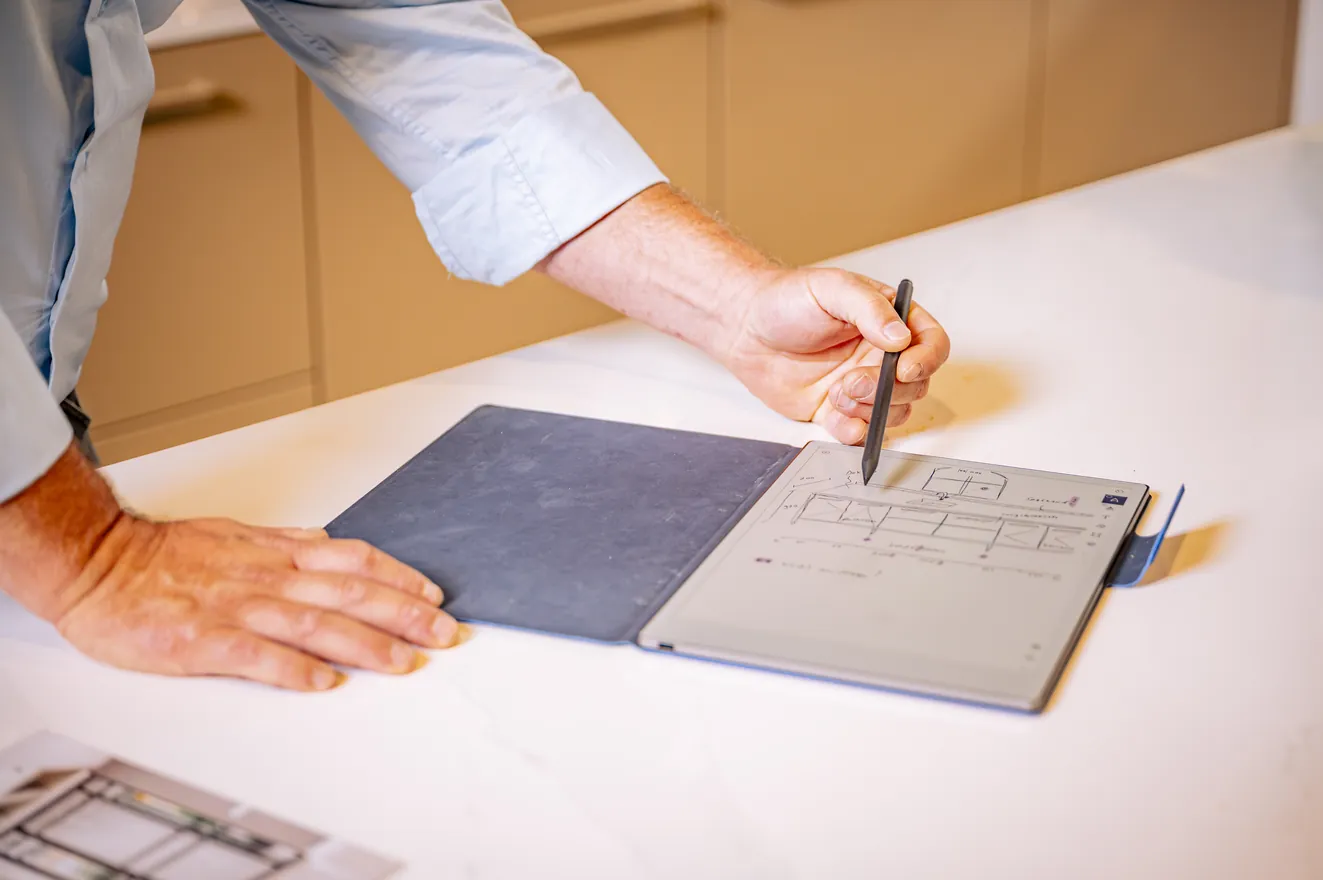 Henk van Veen tekent met een pen op een tablet op het aanrecht